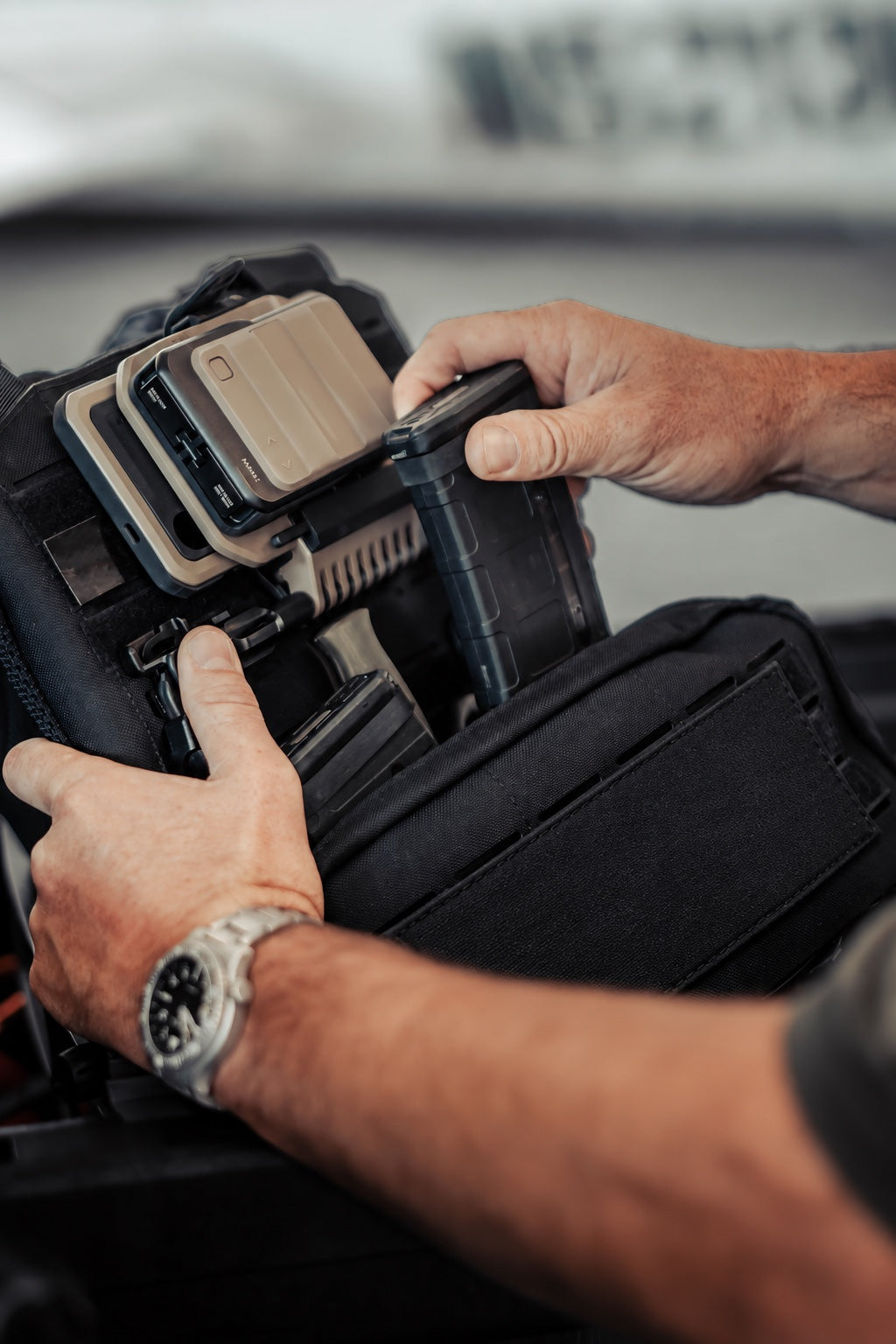 Hands adjusting equipment mounted on a tactical chest rig
