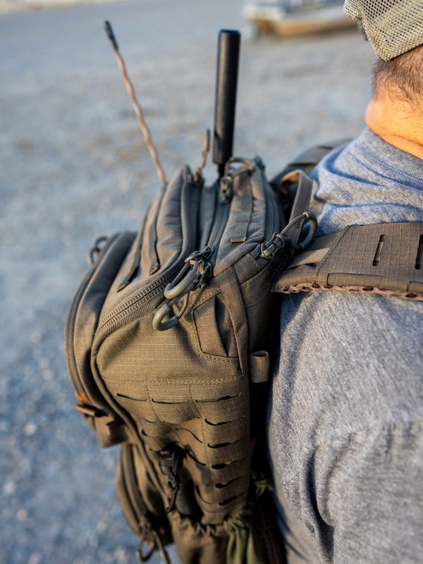 RADIO MANPACK worn on the back, whip antenna up — the node moves with you
