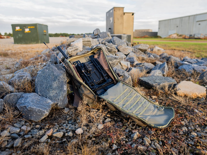 RADIO MANPACK deployed open on the rock pile, antennas up, relaying on site