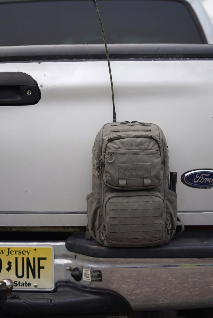 RADIO MANPACK zipped inside the Eberlestock R4 ROMAD, sitting against the truck with the antenna up